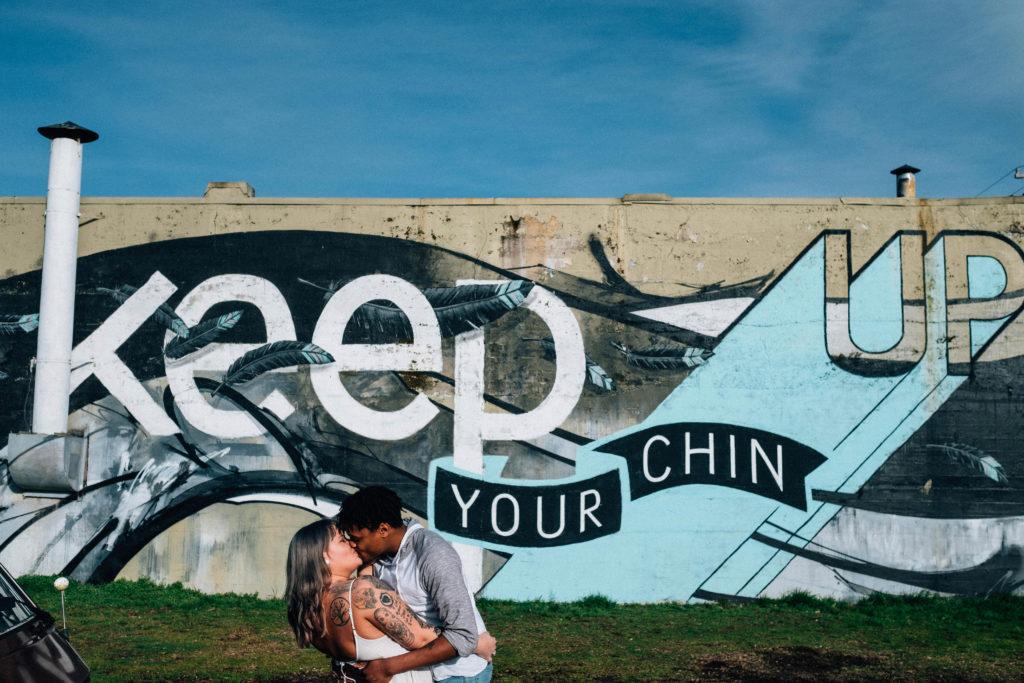 Engagement photo with the "Keep your chin up" mural on Alberta Street