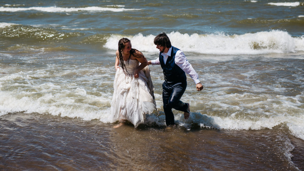 Bride and groom jumping into Lake Michigan after their wedding