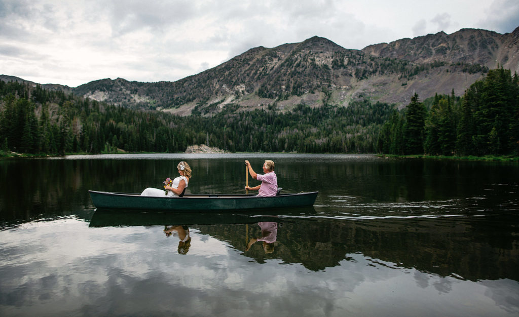 Bride in a canoe going to her wedding ceremony at Branham Lake Campground in Sheridan, MT