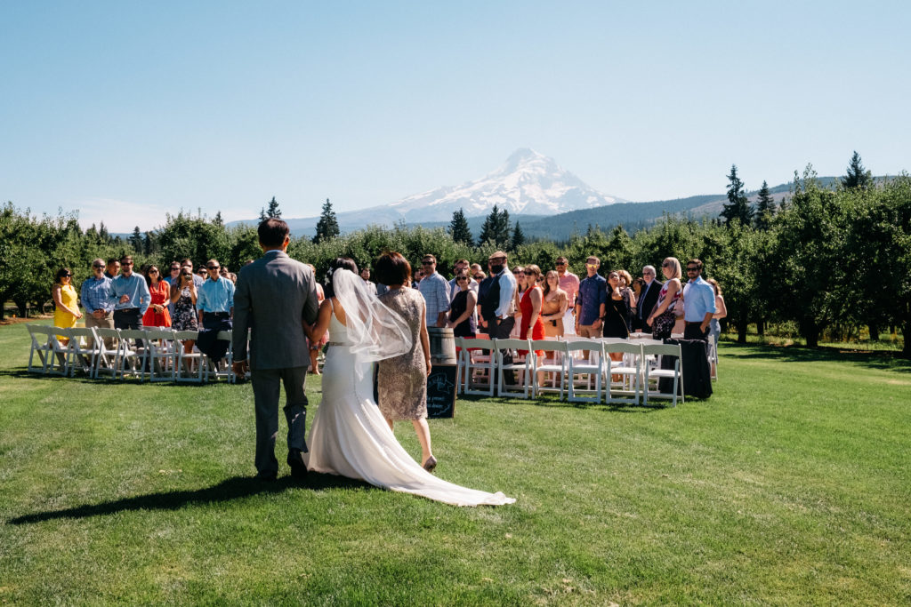 A bride walking down the aisle with Mount Hood at her Mt View Orchards wedding