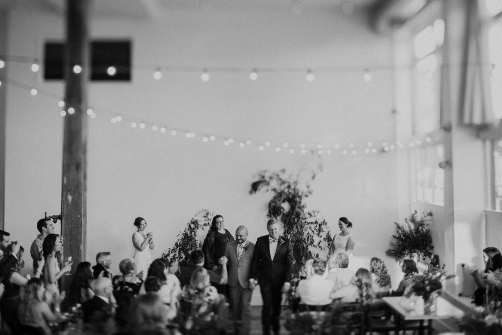 Two grooms walking down the aisle after their wedding ceremony at The Cleaners at the Ace Hotel