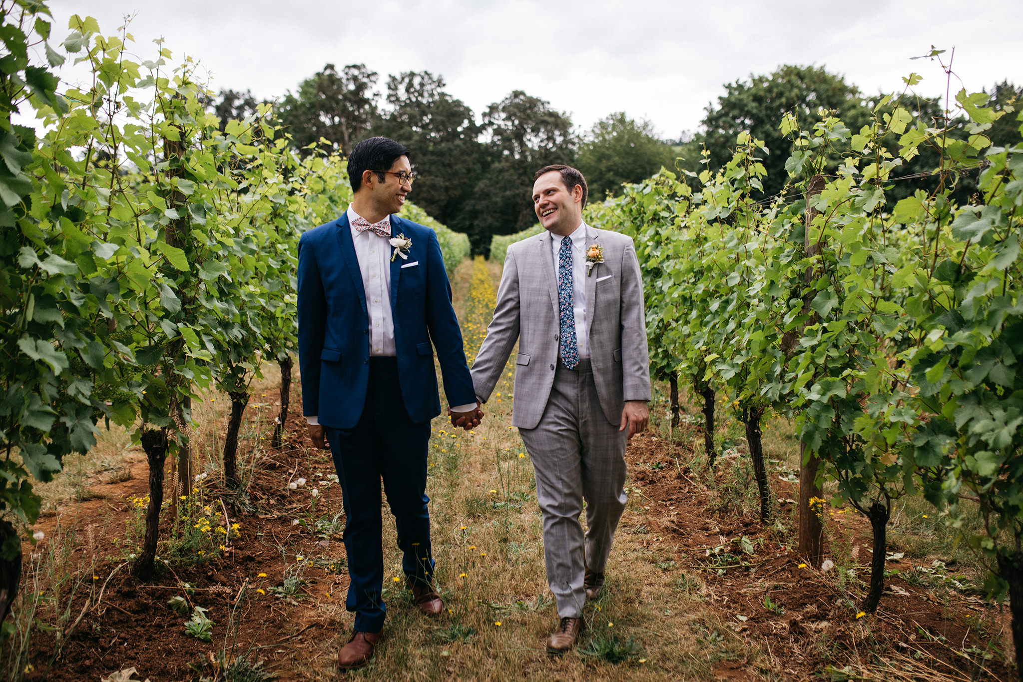 A photo of two grooms walking in the vineyard at Red Ridge Farms