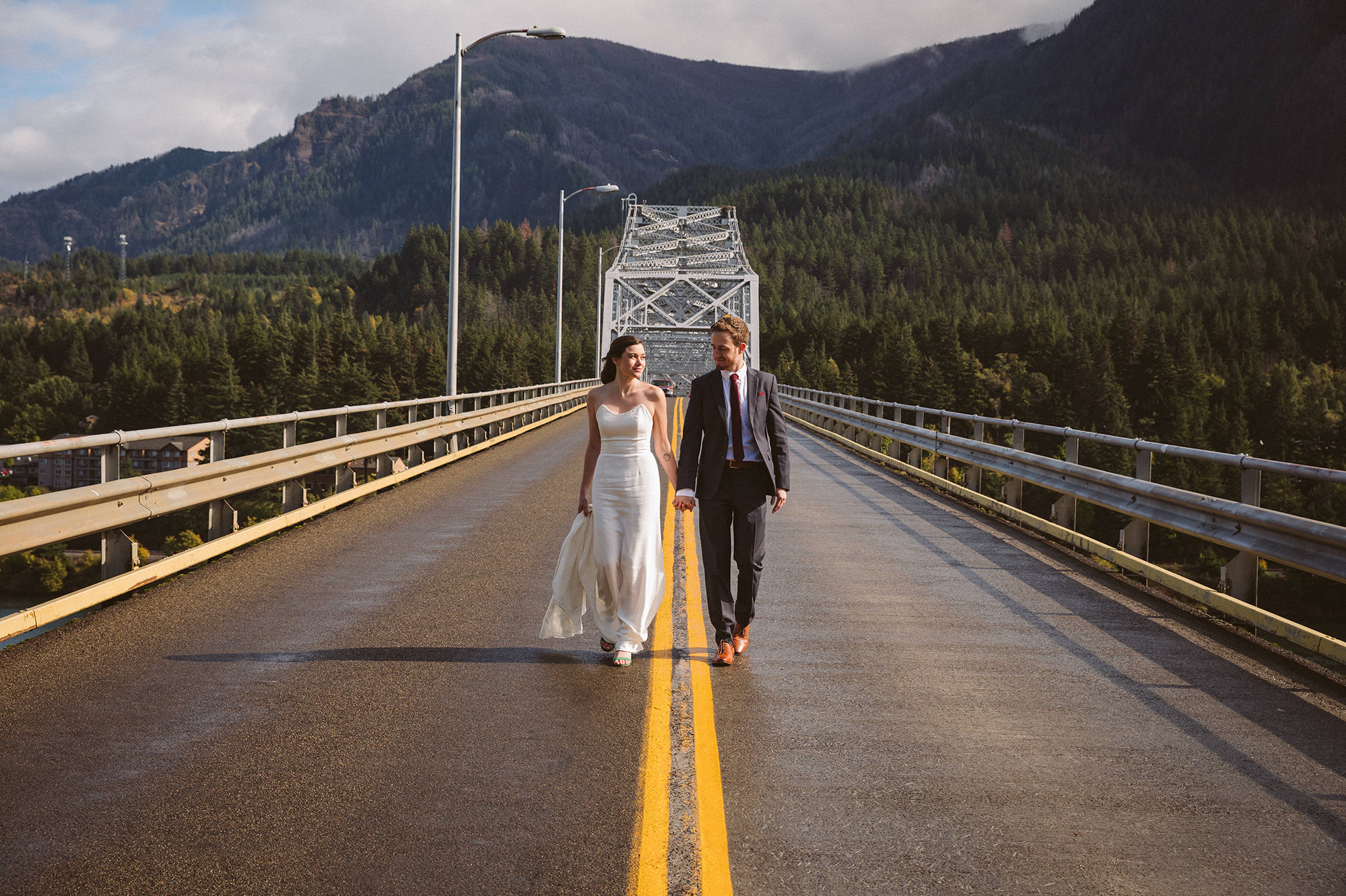 A bride and groom walking on the Bridge of the Gods over the Columbia River