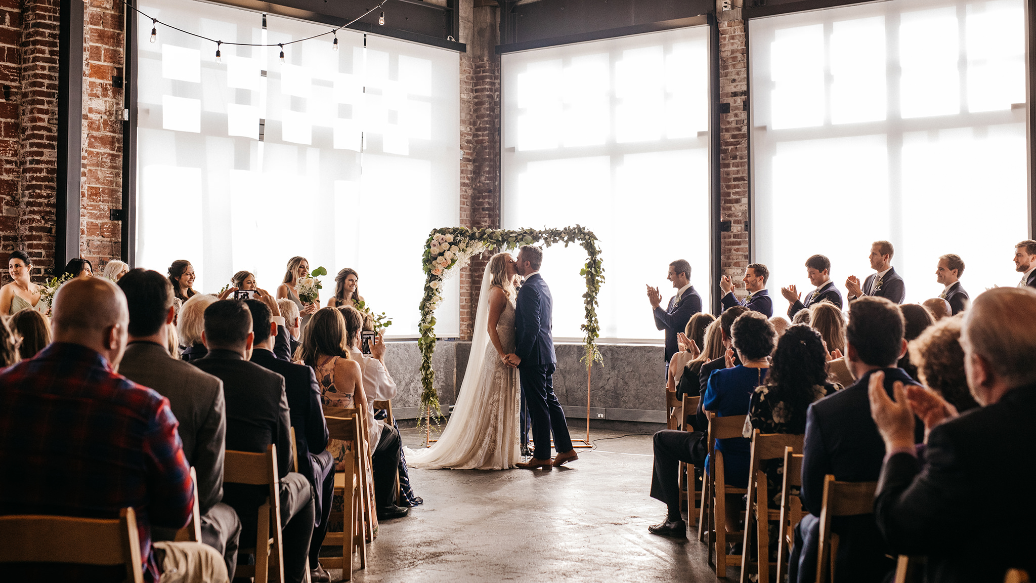 A bride and groom's first kiss during their Leftbank Annex wedding ceremony, an industrial Portland wedding venue