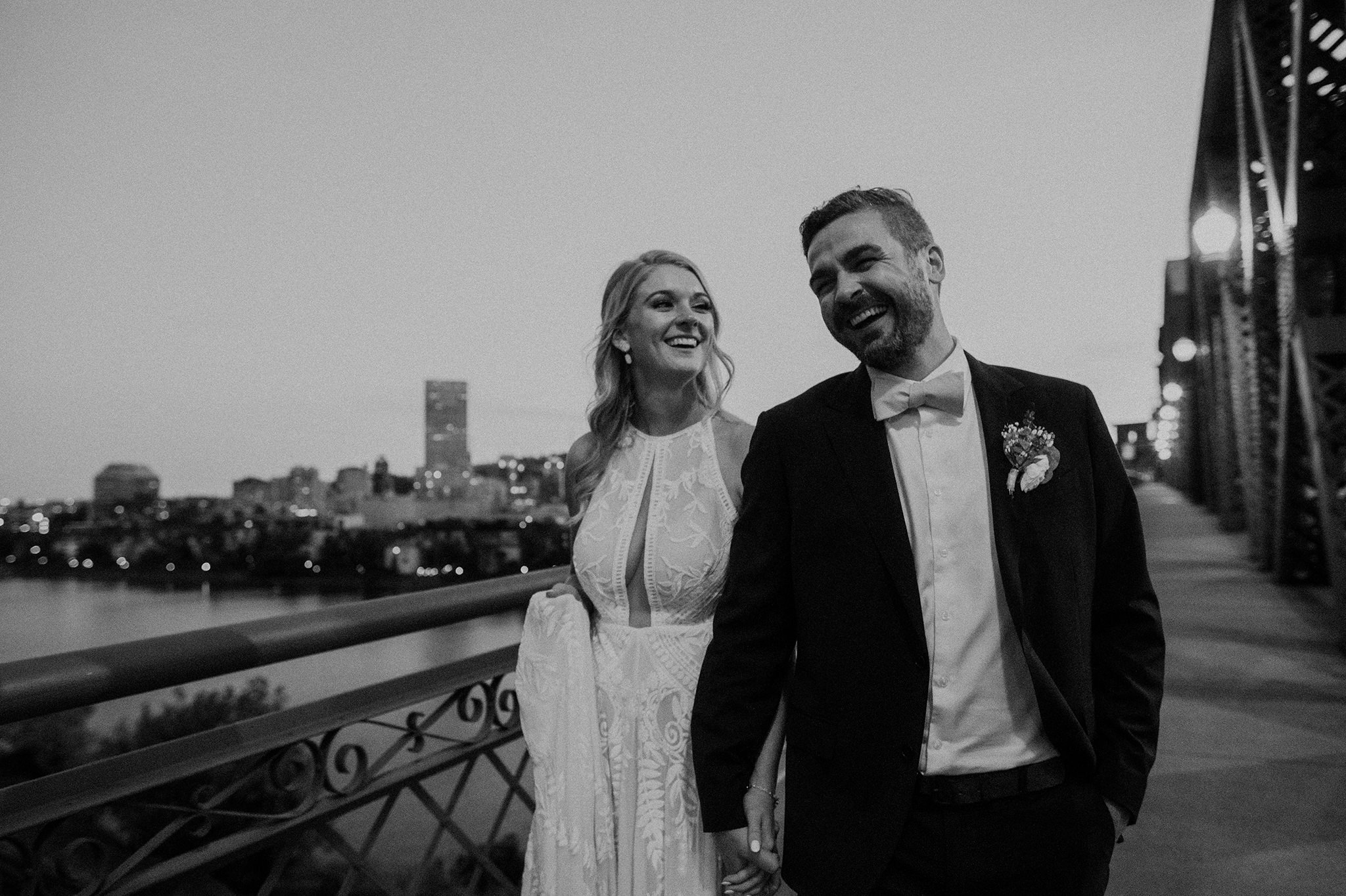 A bride and groom walking on the broadway bridge with the city skyline of Portland, Oregon in the background