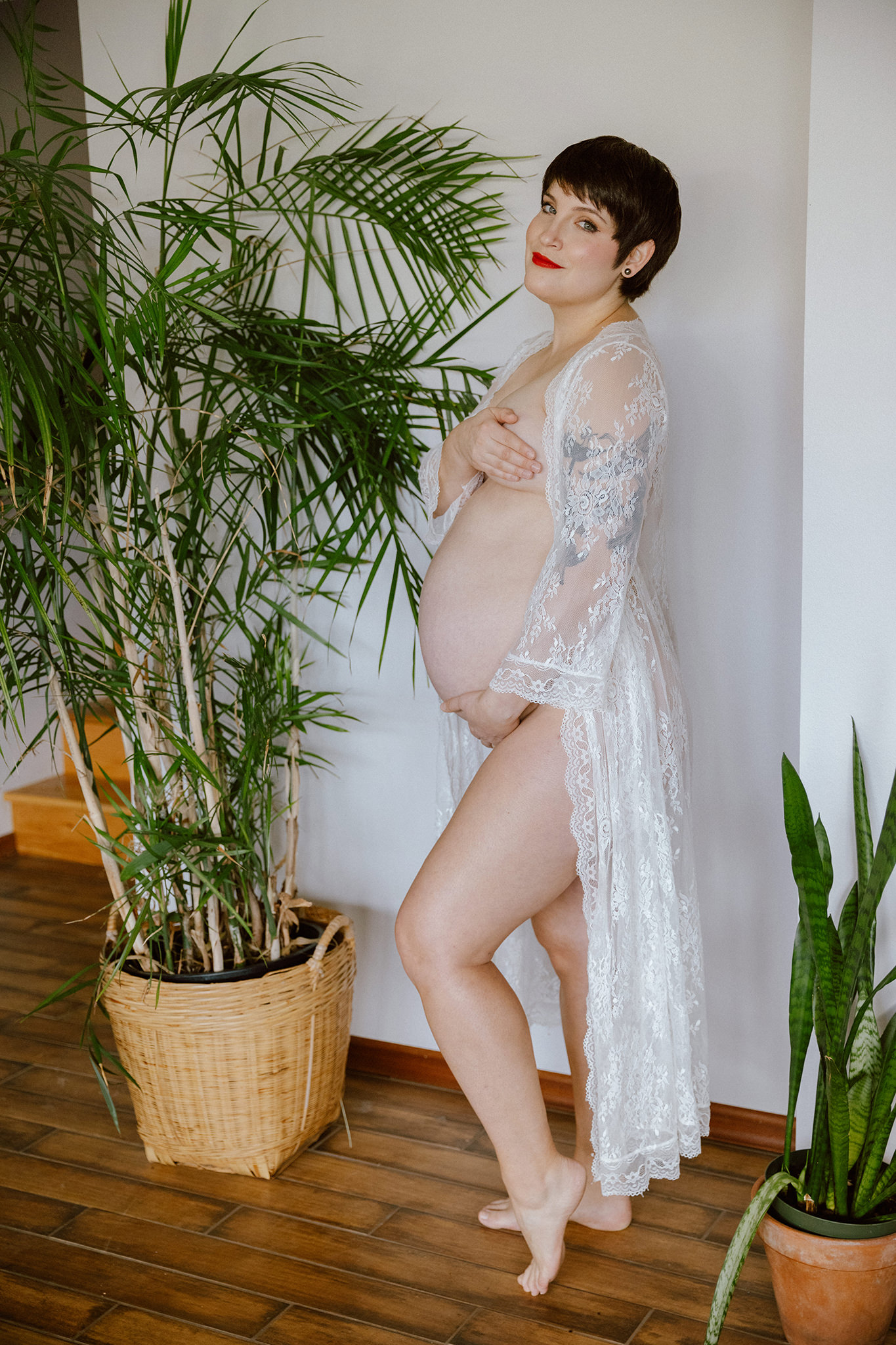 Sexy boudoir maternity photo in a lace robe with plants and natural light