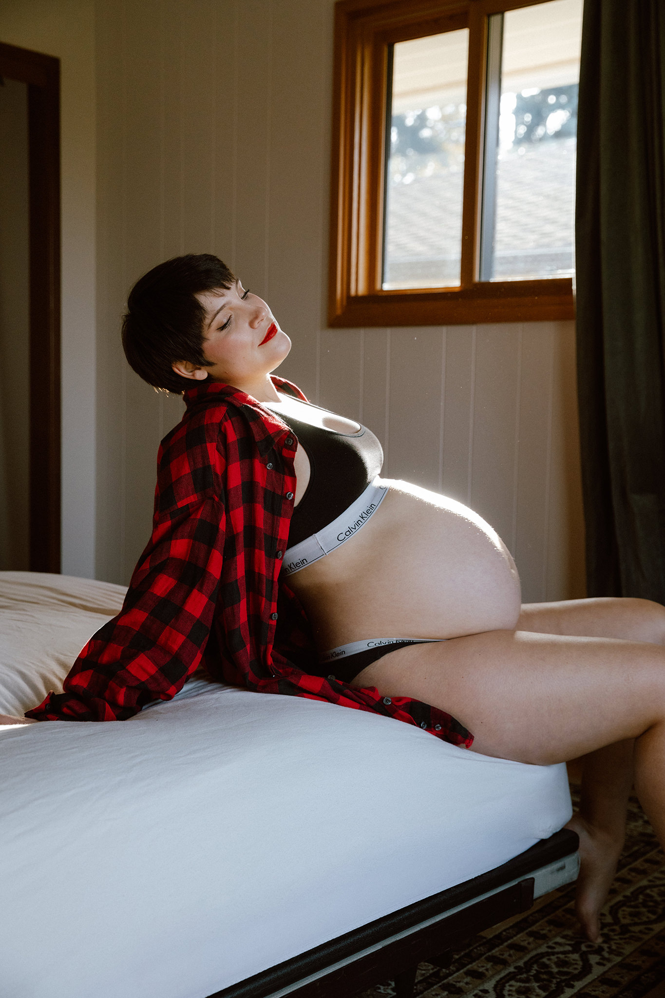 Intimate boudoir maternity photo on a bed with natural light