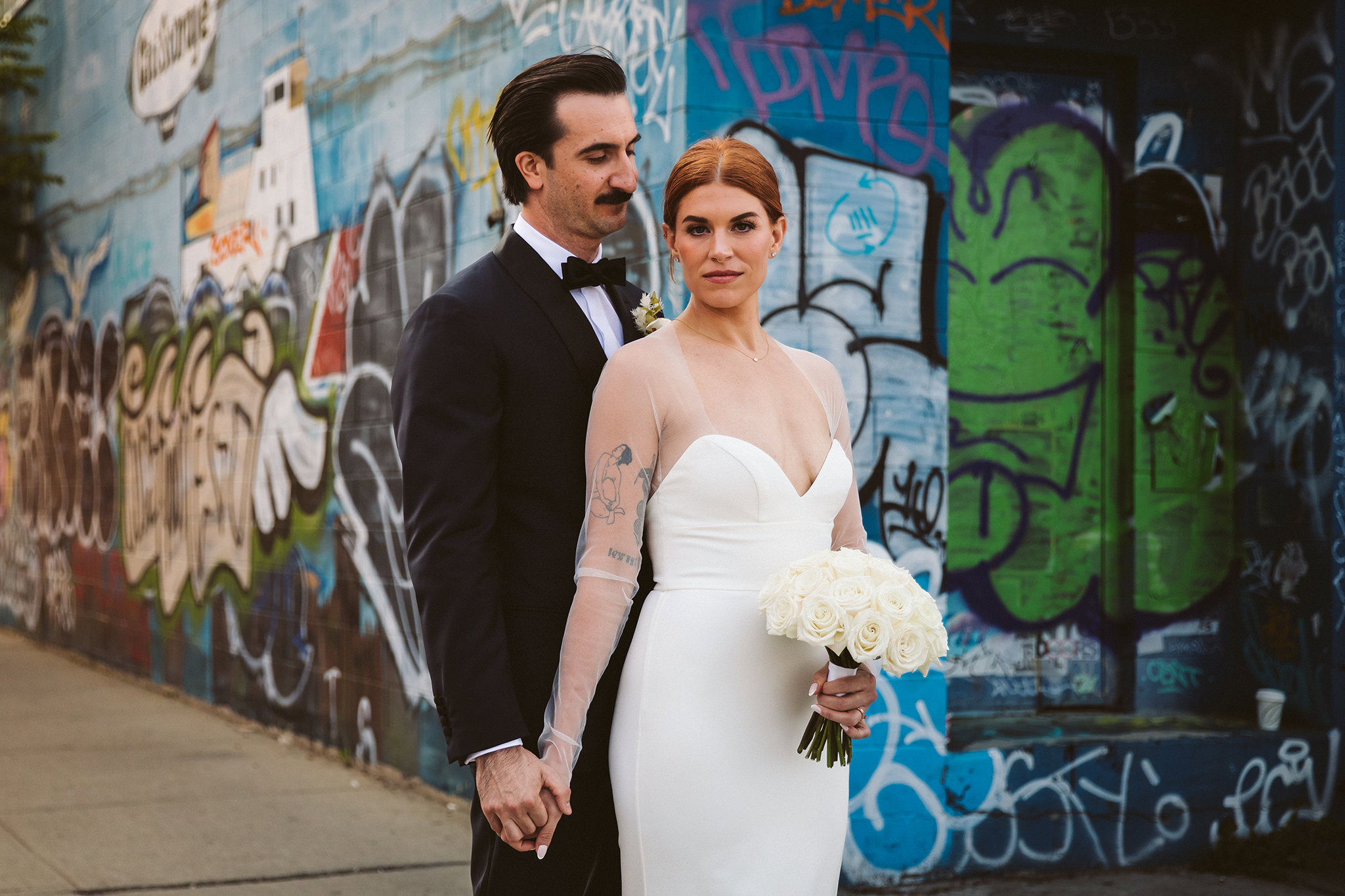 A portrait of a bride and groom in front of graffiti during their Williamsburg wedding in Brooklyn