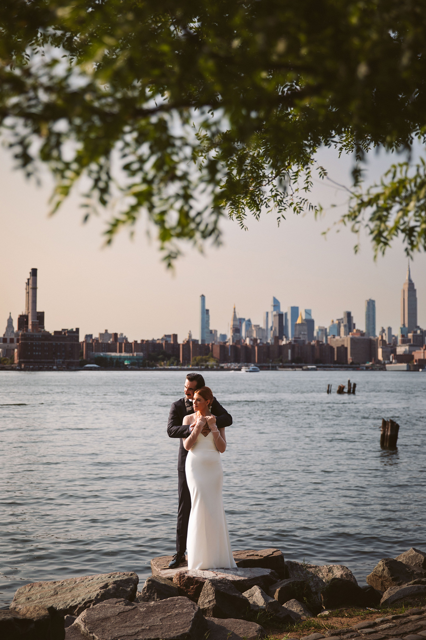 A sunny wedding photo of a bride and groom on the East River near the Wythe Hotel in New York