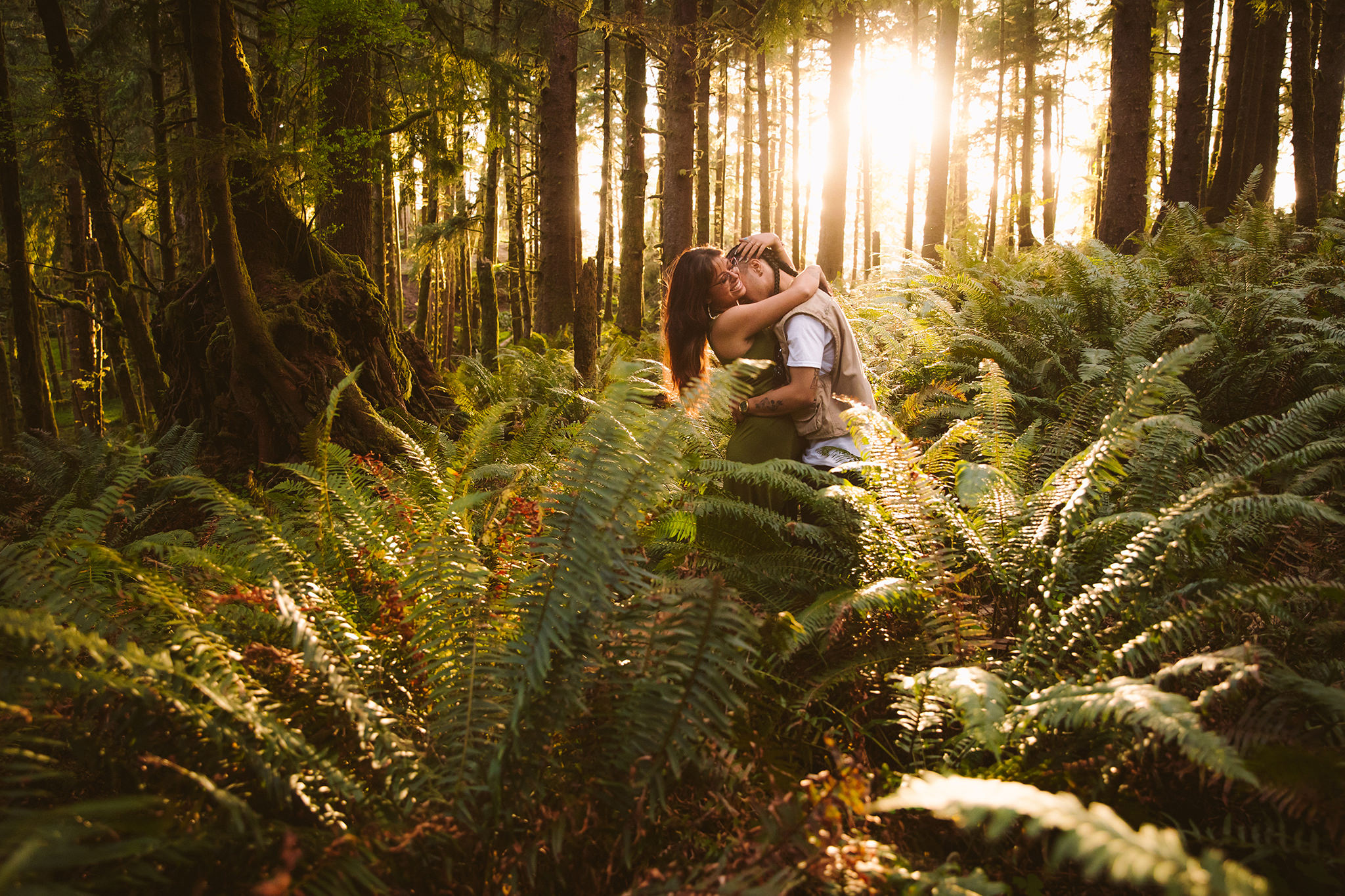 A couple hugging in a bed of ferns in Ecola State Park