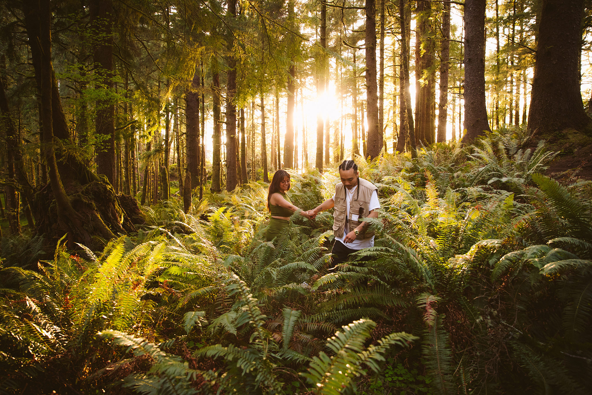 A couple walking through ferns during their Oregon forest engagement session
