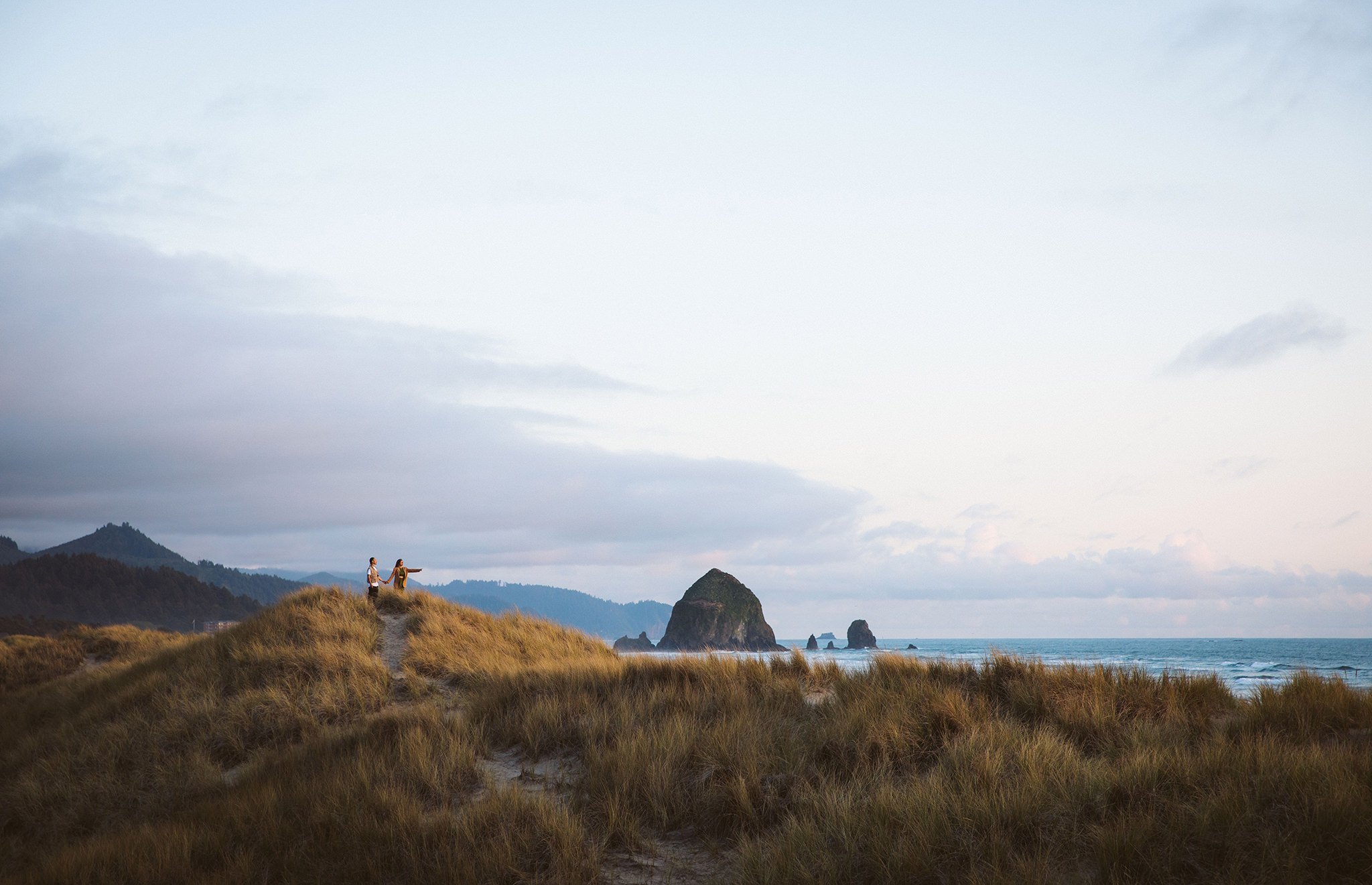 An engagement photo in the sand dunes at Cannon Beach in Oregon