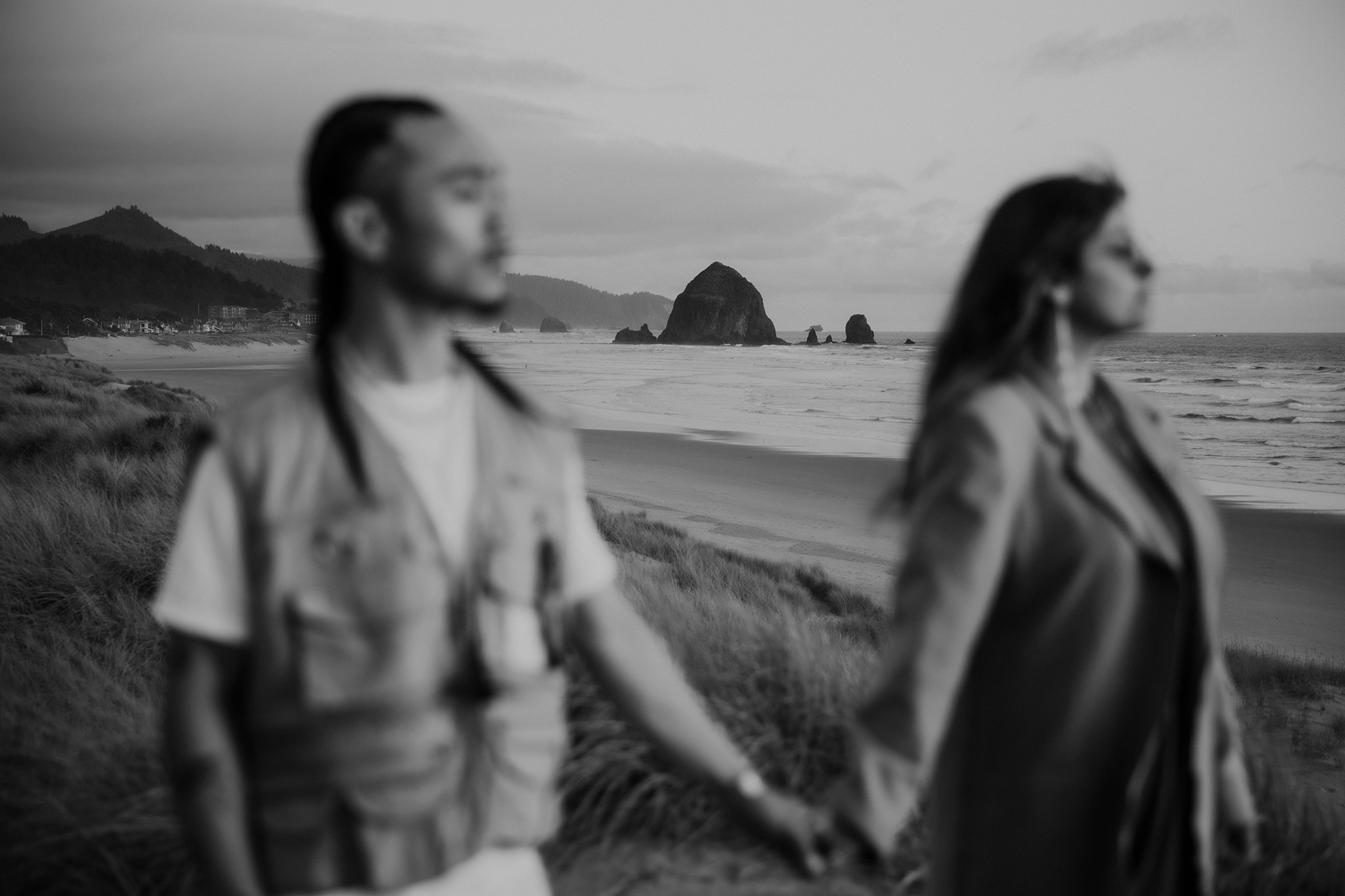 A black and white photo of a couple in front of Haystack Rock on Cannon Beach