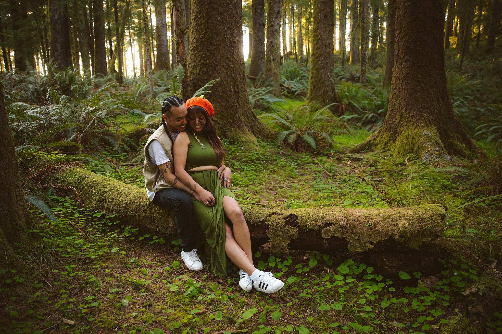 A couple sitting on a moss covered log in the Oregon woods near Cannon Beach