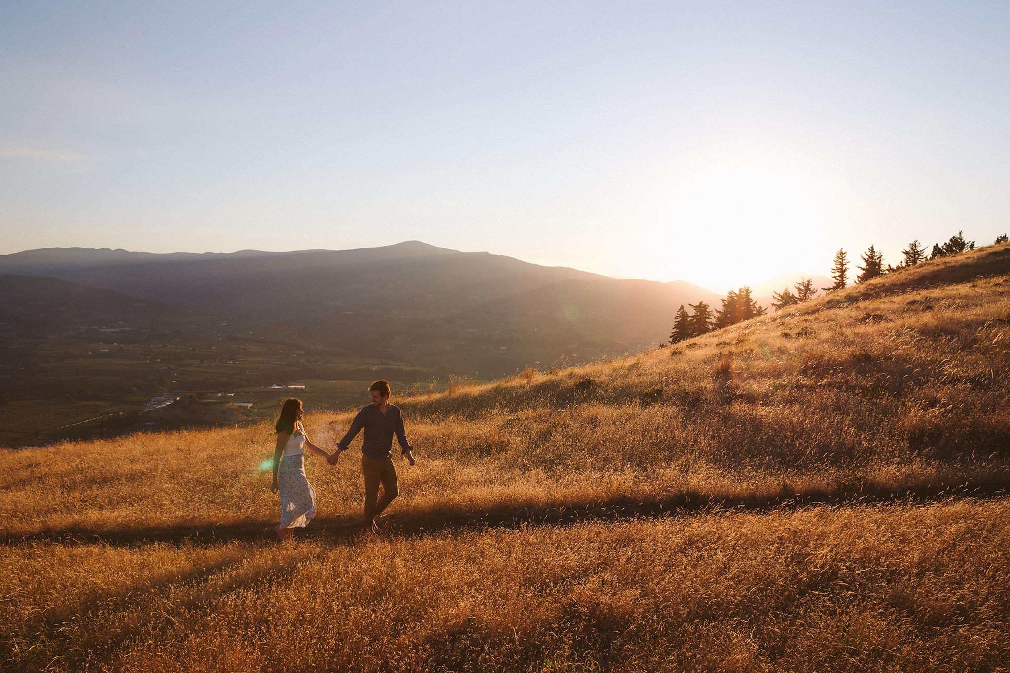 A couple walking through a wheat field during their golden hour engagement session in Hood River, Oregon