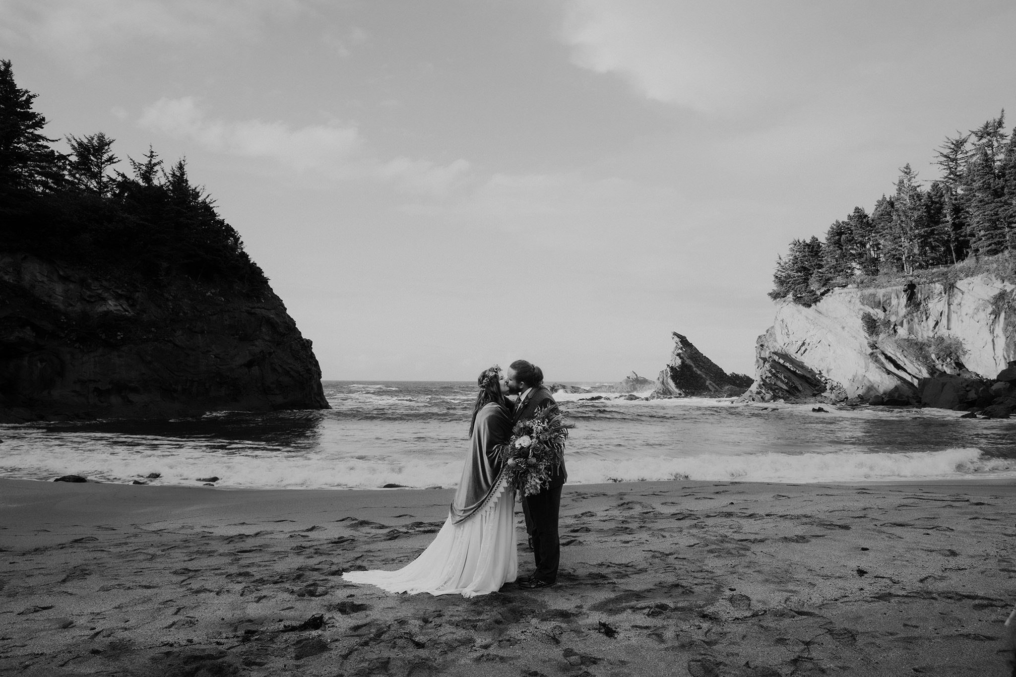 A black and white photo of a first kiss during an Oregon coast elopement ceremony