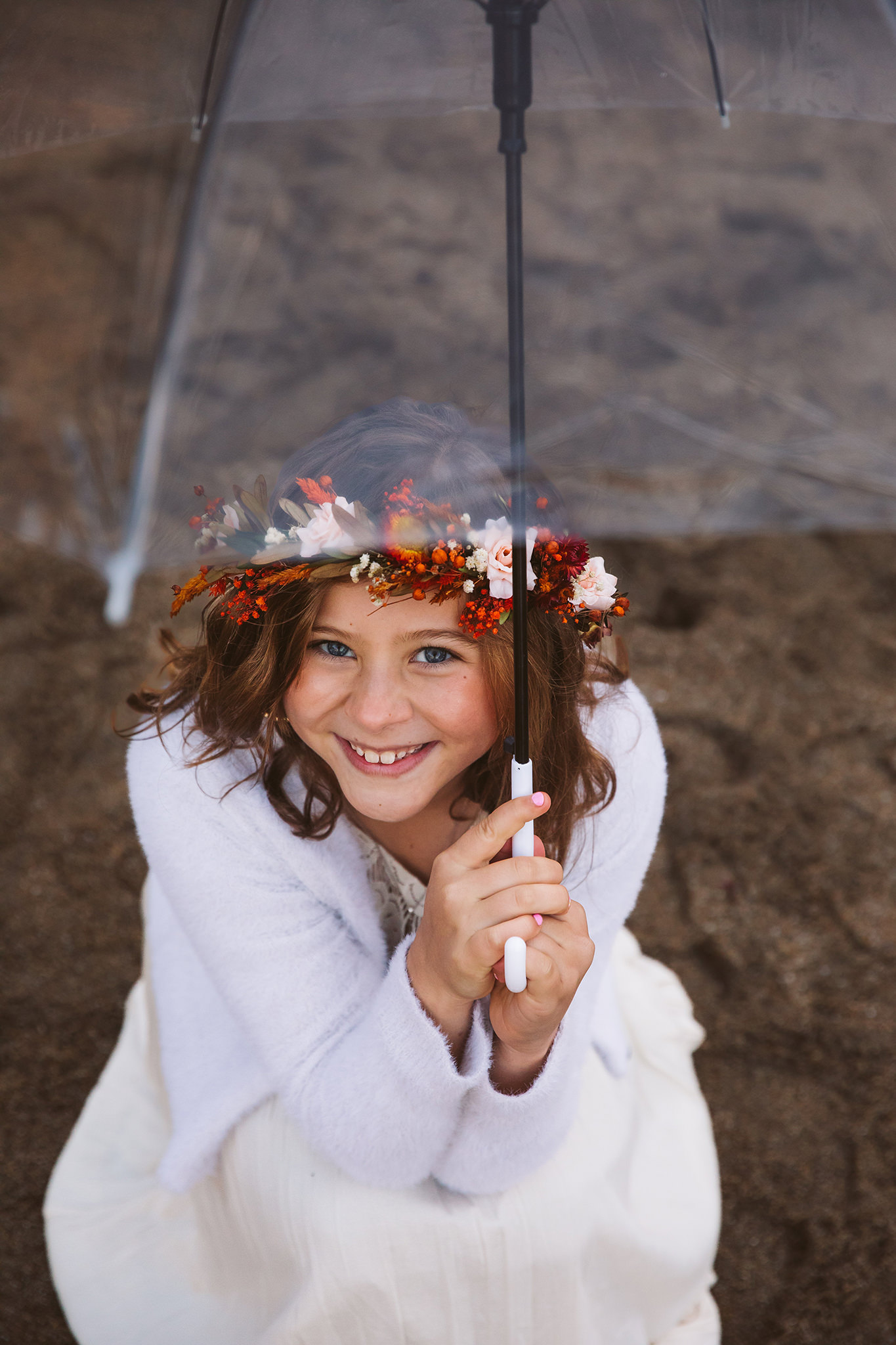 A flower girl in the rain with a clear umbrella at an Oregon coast elopement ceremony