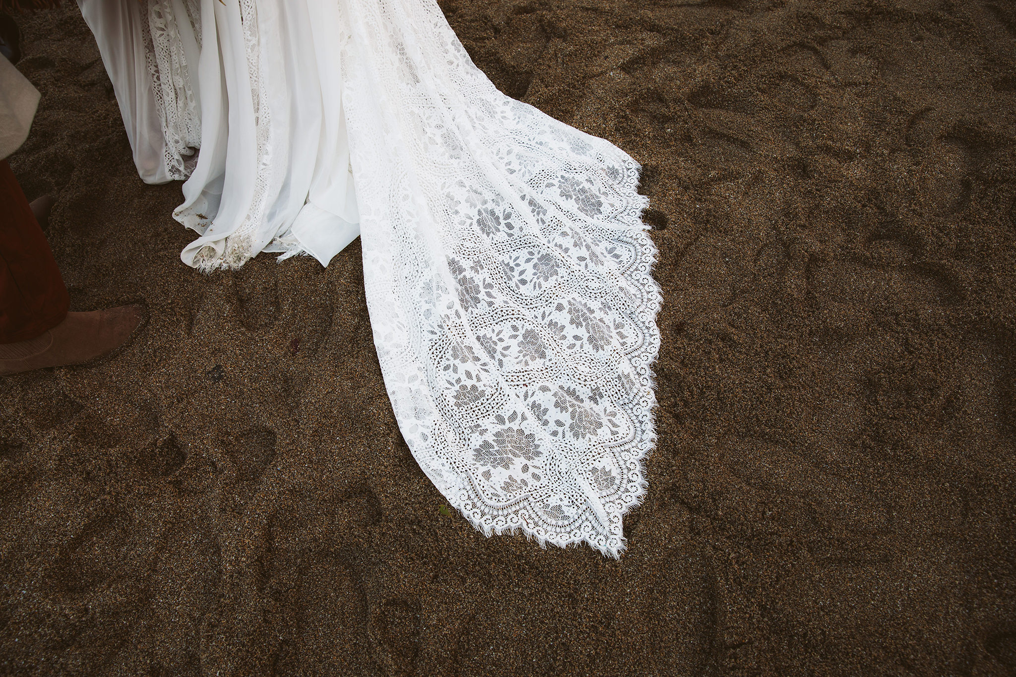 A wet wedding dress in the sand at an Oregon elopement on the beach