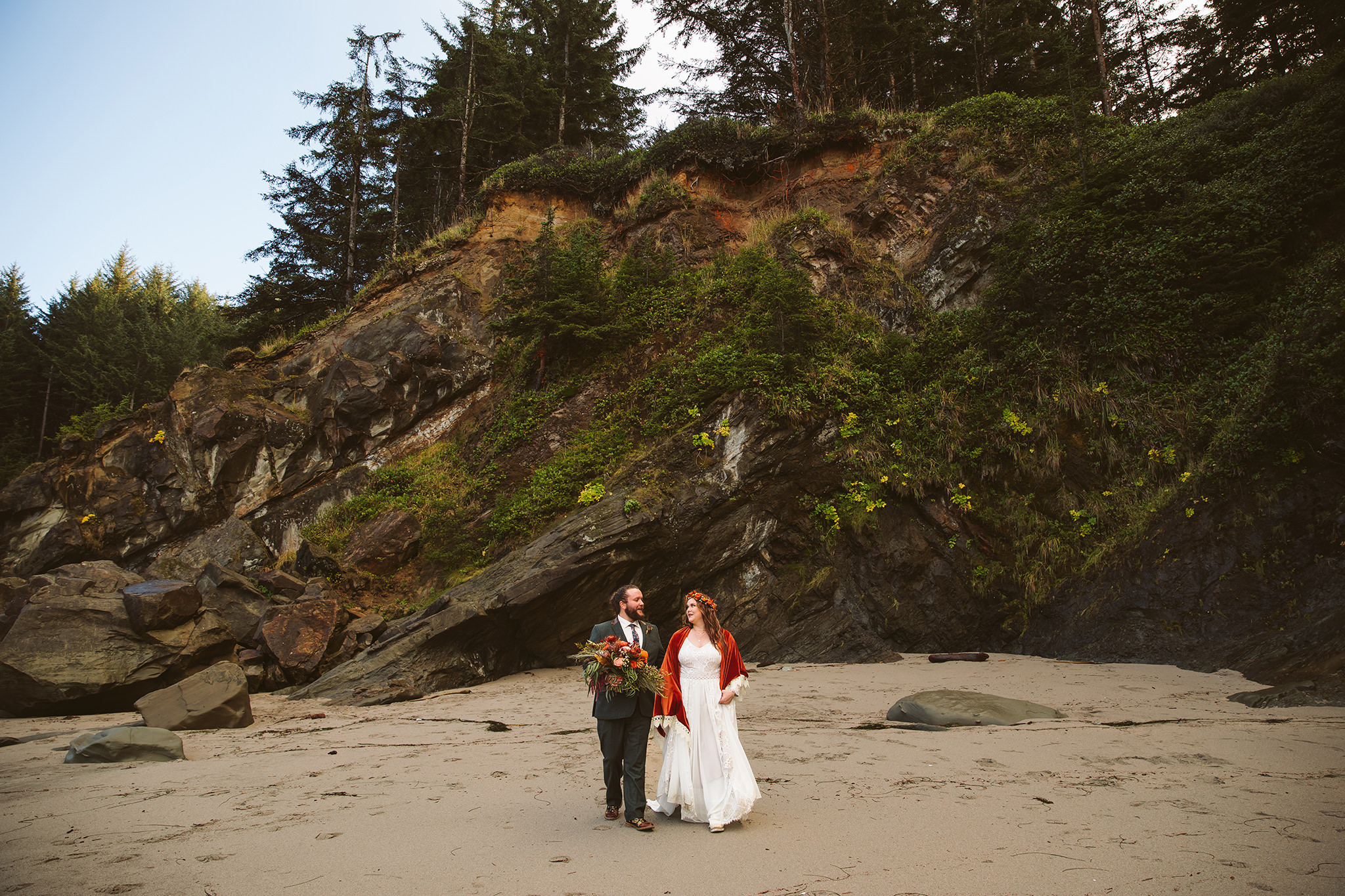 A bride and groom walking on the beach during their Pacific Northwest elopement ini Oregon