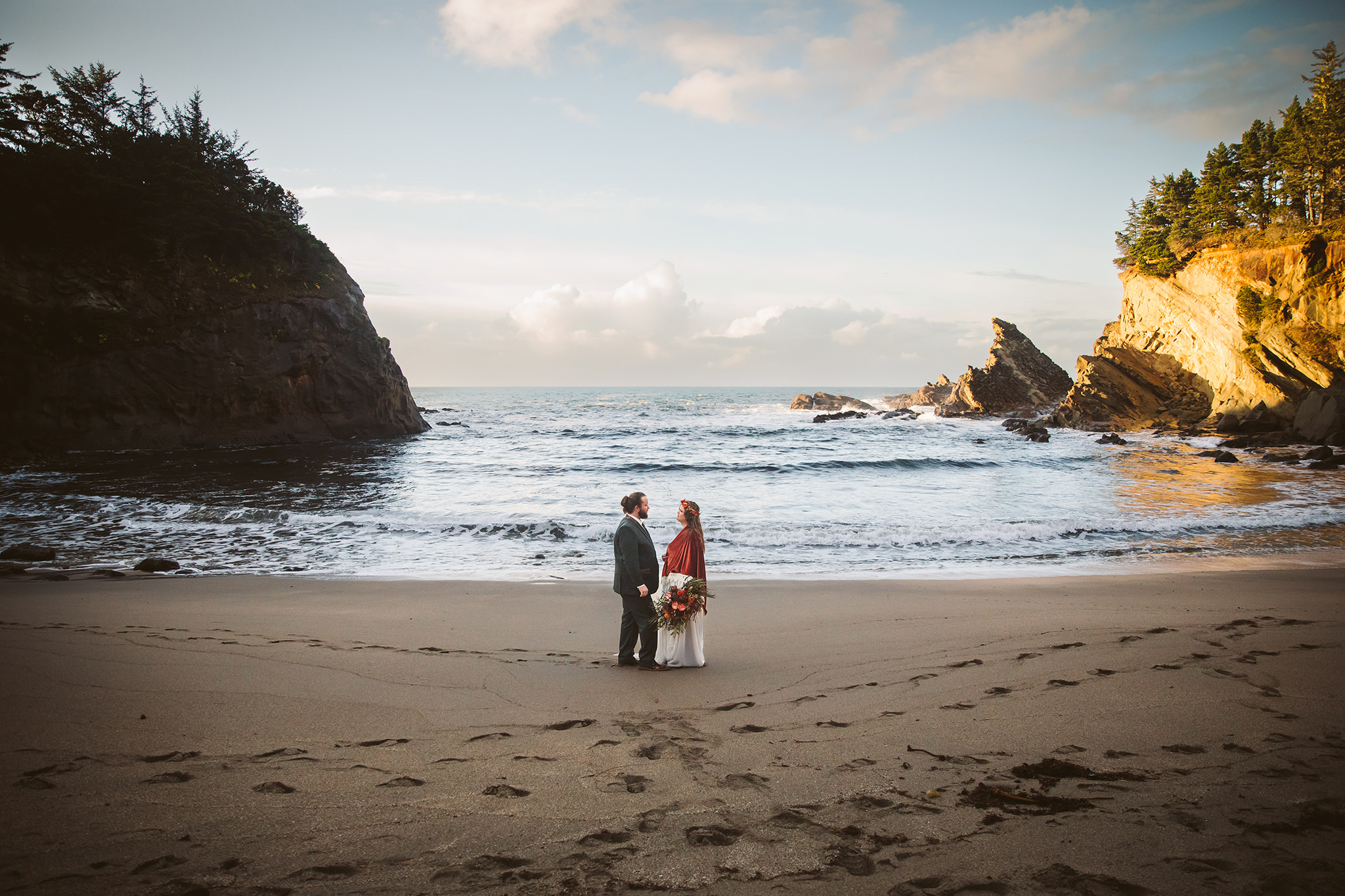 A wedding photo of a bride and groom in a beach alcove on the Southern Oregon coast