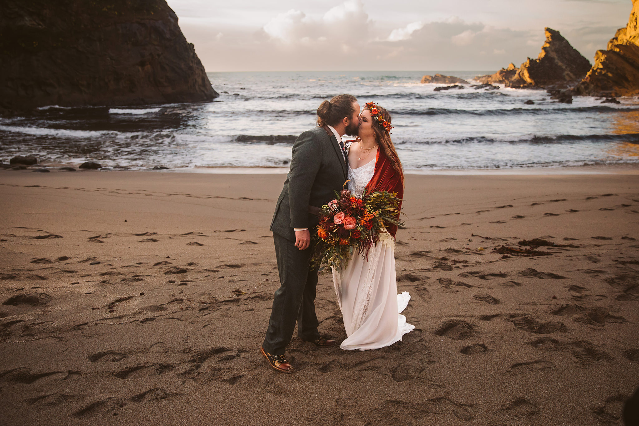 A wedding photo of a bride and groom kissing at sunset on the Oregon coast